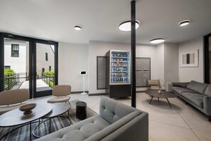 A modern living room with a sofa, armchairs, a coffee table, and a bookshelf.