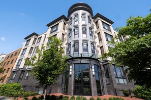 A modern building with a curved corner entrance, large windows, and a sign reading "818 Reside Navy Yard."