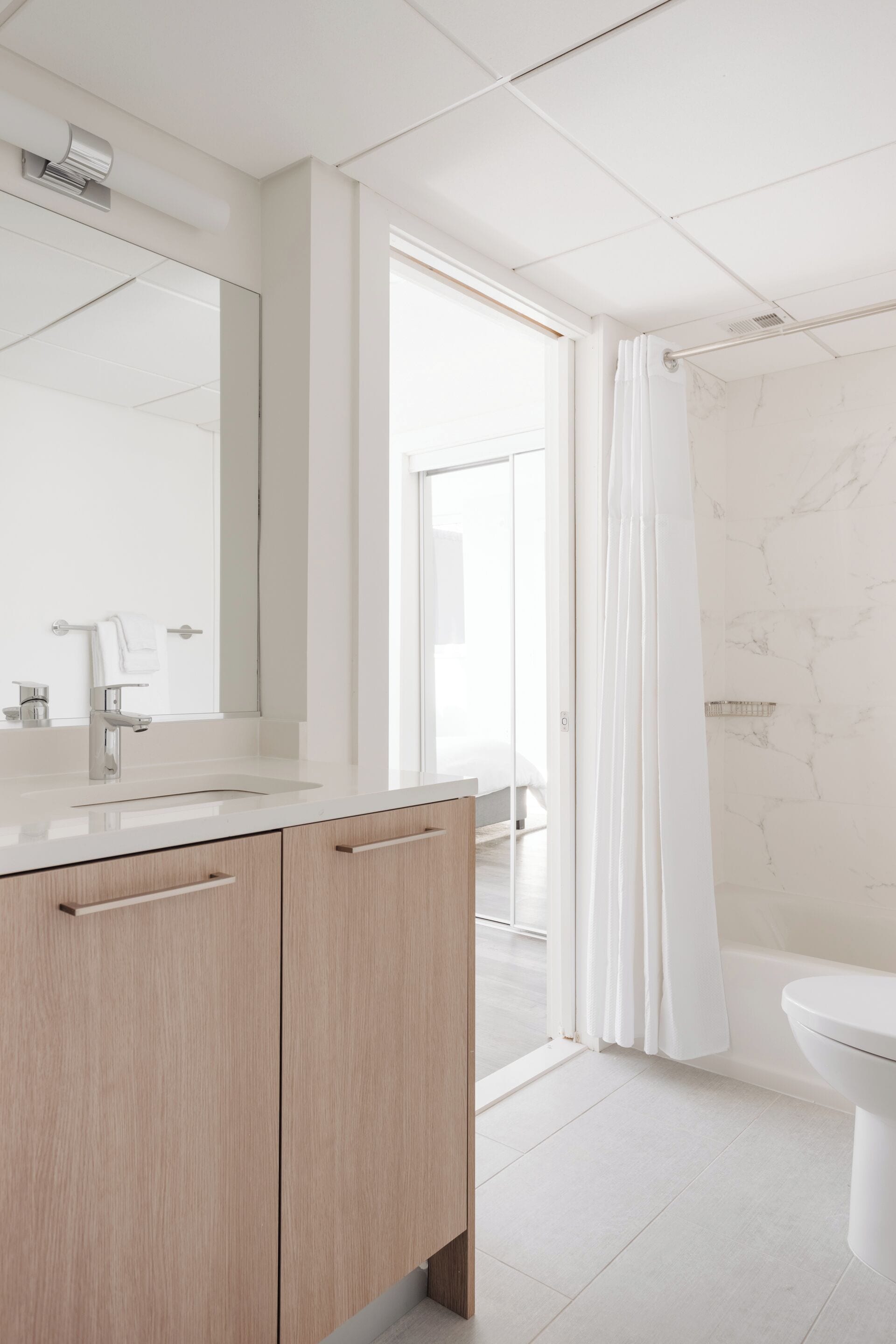 A modern bathroom with a large mirror, a sink, and a toilet.