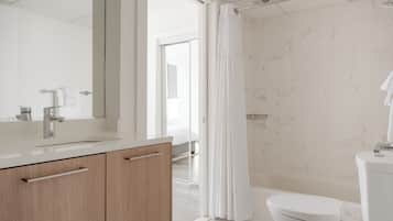 A modern bathroom with a marble wall, a white sink, and a toilet.