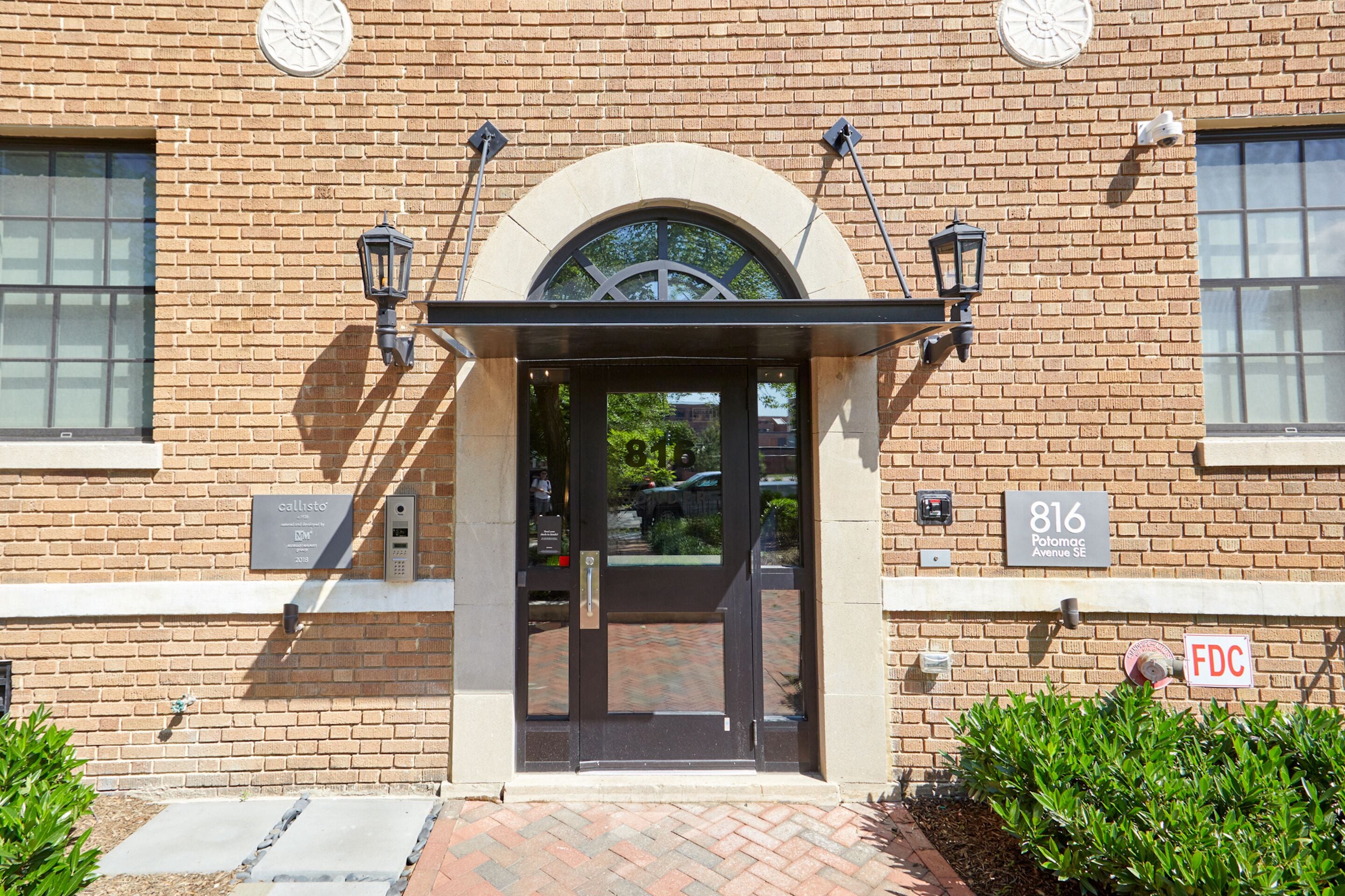 A brick building with a glass door entrance, a sign reading "816 Polomac Avenue SE", and a "DFC" sign.