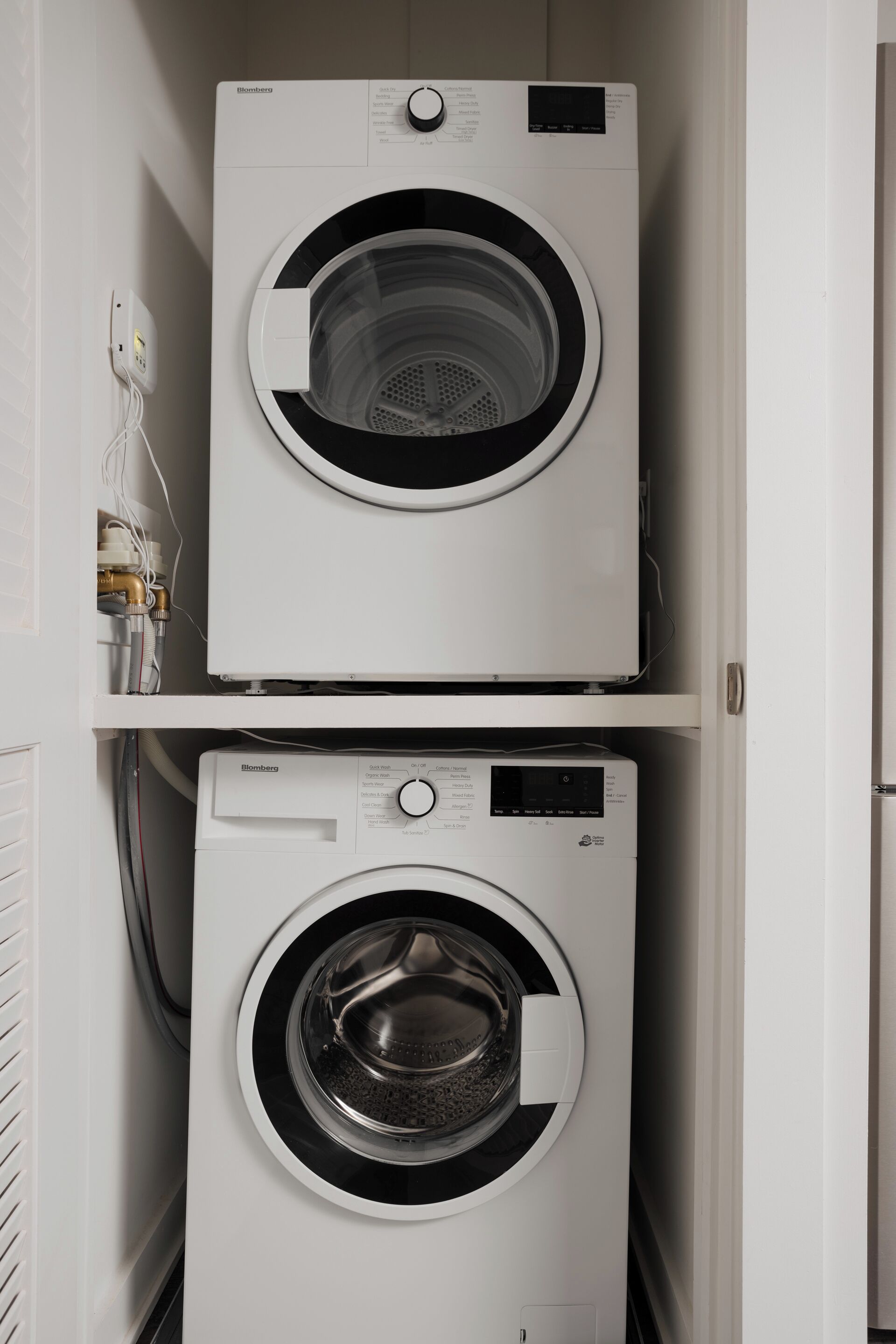 Two stacked front-loading washing machines in a laundry room.