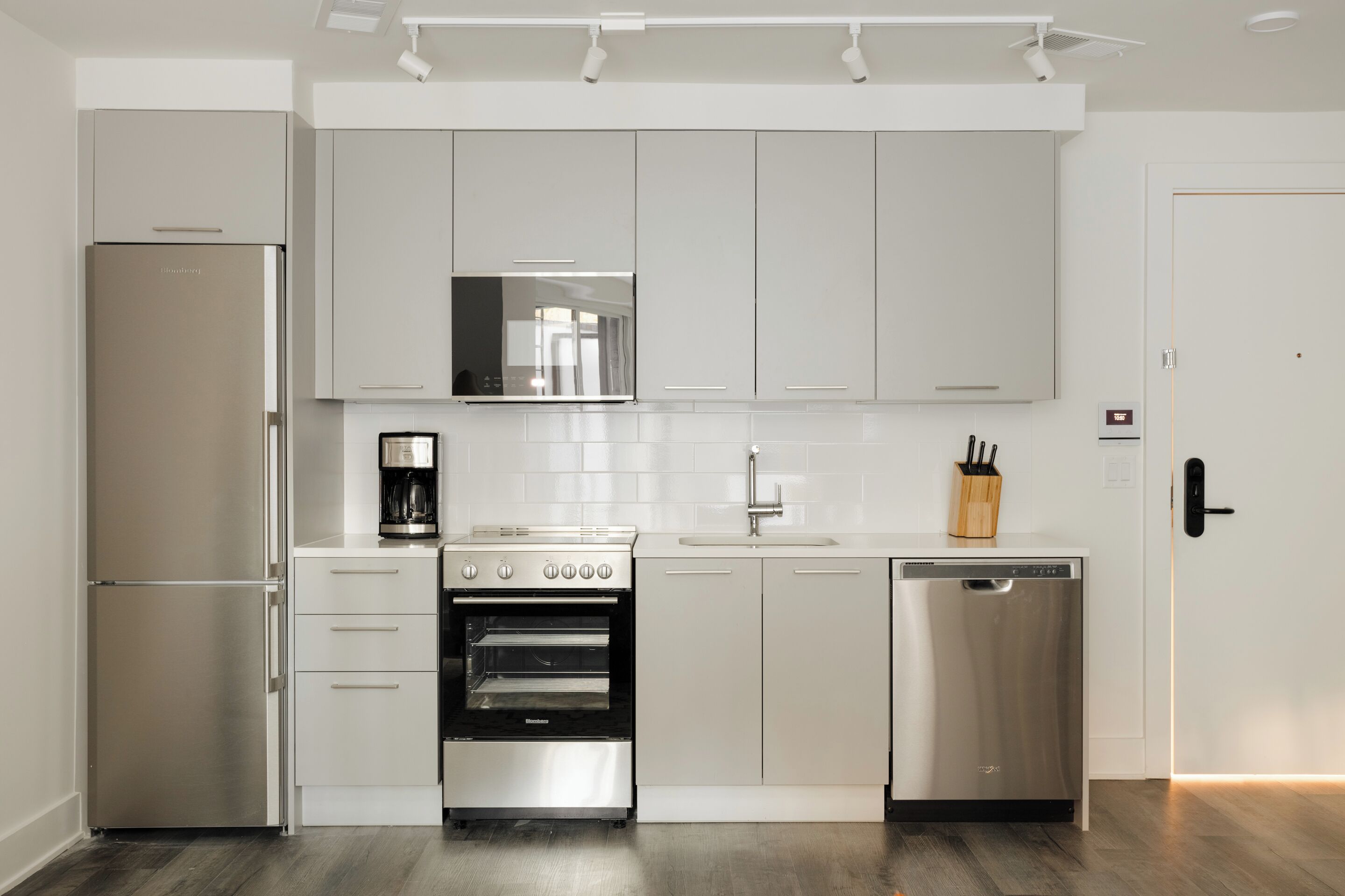 A modern kitchen with stainless steel appliances, white cabinetry, and a built-in oven.