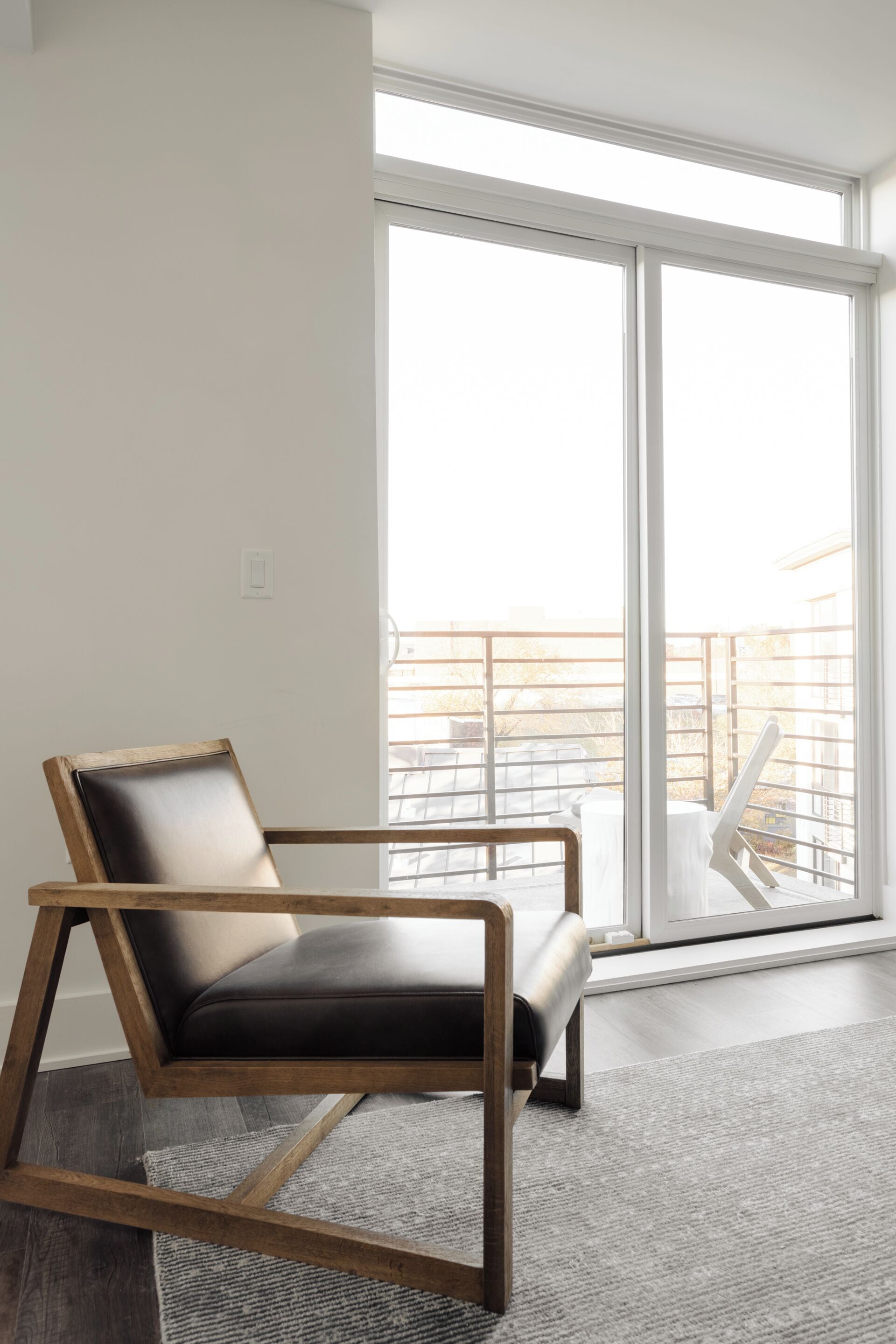 Una sala de estar moderna con un sofá de cuero, una mesa de centro de madera y un amplio ventanal corredero que da a un balcón.