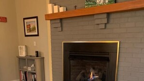 Un salon avec une cheminée, une bibliothèque et un plaid à motifs sur le canapé.