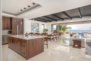 Uma cozinha moderna com uma ilha grande, armários de madeira e um espaço de refeições com cadeiras e mesa.