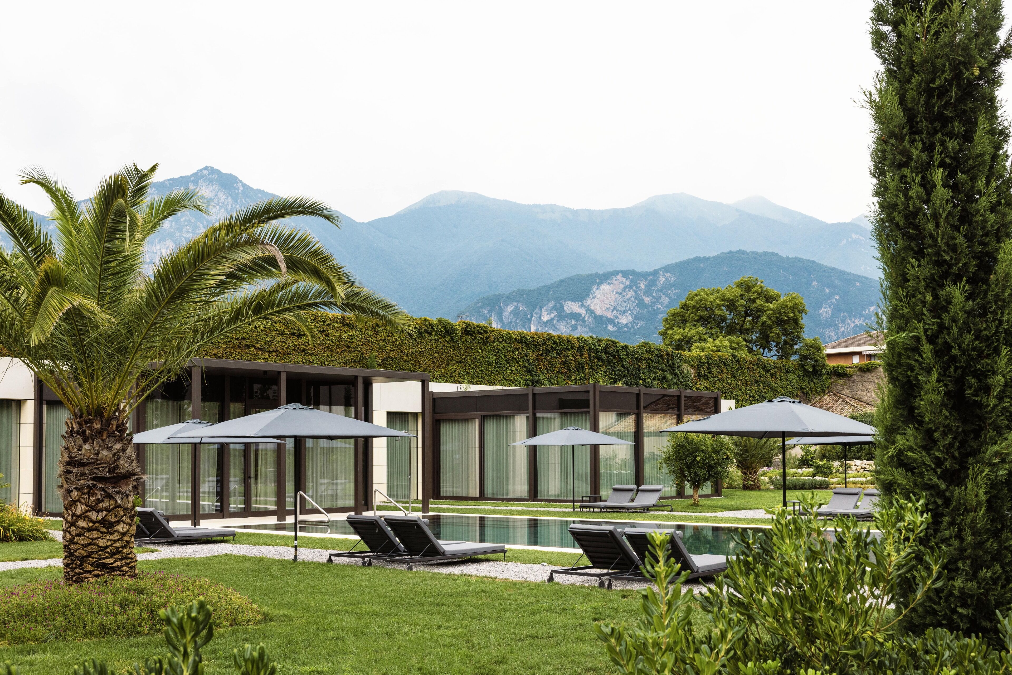 Ein modernes Resort mit Pool, Liegestühlen und Blick auf die Berge.