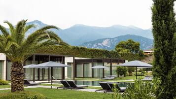 Ein modernes Resort mit Pool, Liegestühlen und Blick auf die Berge.