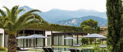 A modern resort with a pool, lounge chairs, and a mountain view.