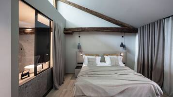 Een moderne slaapkamer met een groot bed, een inbouwkbank en een raam met gordijnen.