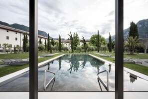 A pool area with a clear view of a building and mountains in the background. - Monastero ARX VIVENDI (Arco)