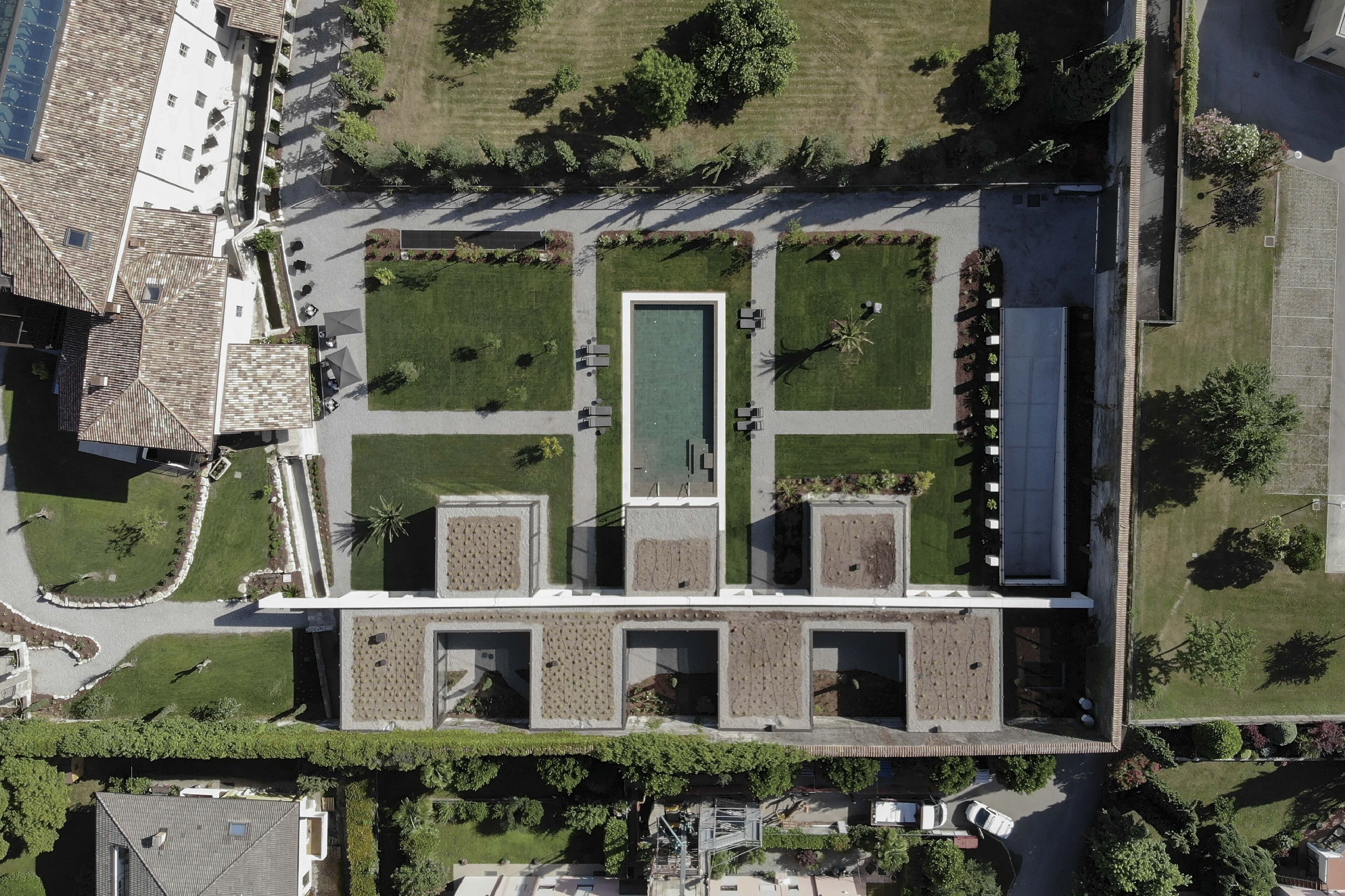 An aerial view of a building with a central courtyard, surrounded by green lawns and pathways.