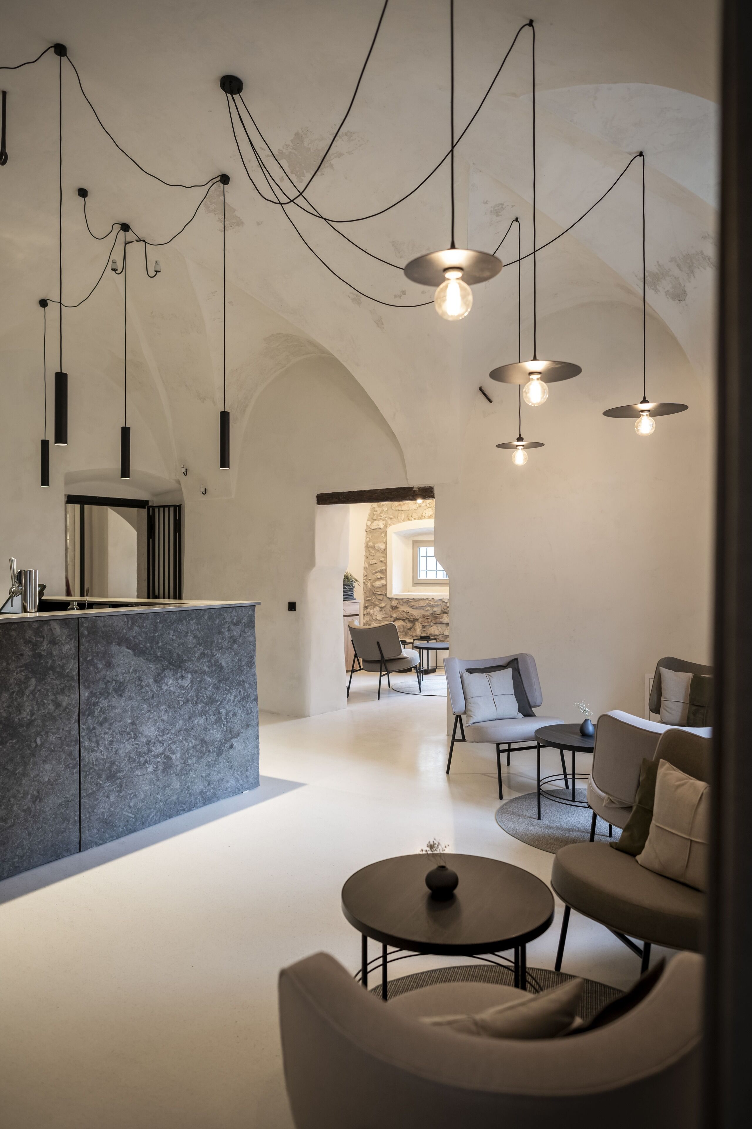 Un interior moderno con zona de cocina, asientos e iluminación colgante.