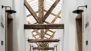 A long, narrow hallway with high ceilings and wooden beams, leading to a central door. - Monastero ARX VIVENDI (Arco)