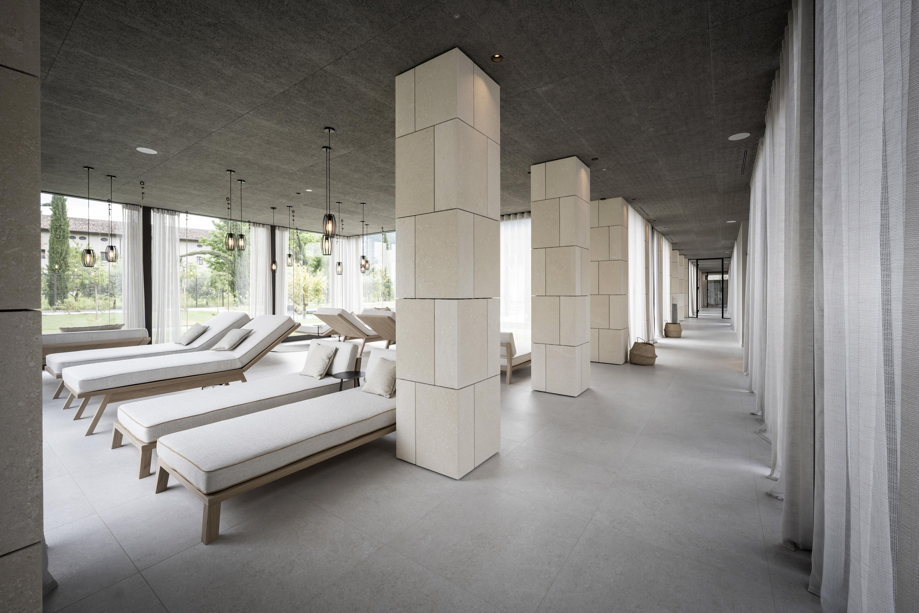 Un spa moderno con varias zonas de descanso, amplias ventanas y un diseño minimalista.