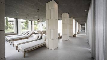 Un spa moderno con varias zonas de descanso, amplias ventanas y un diseño minimalista.