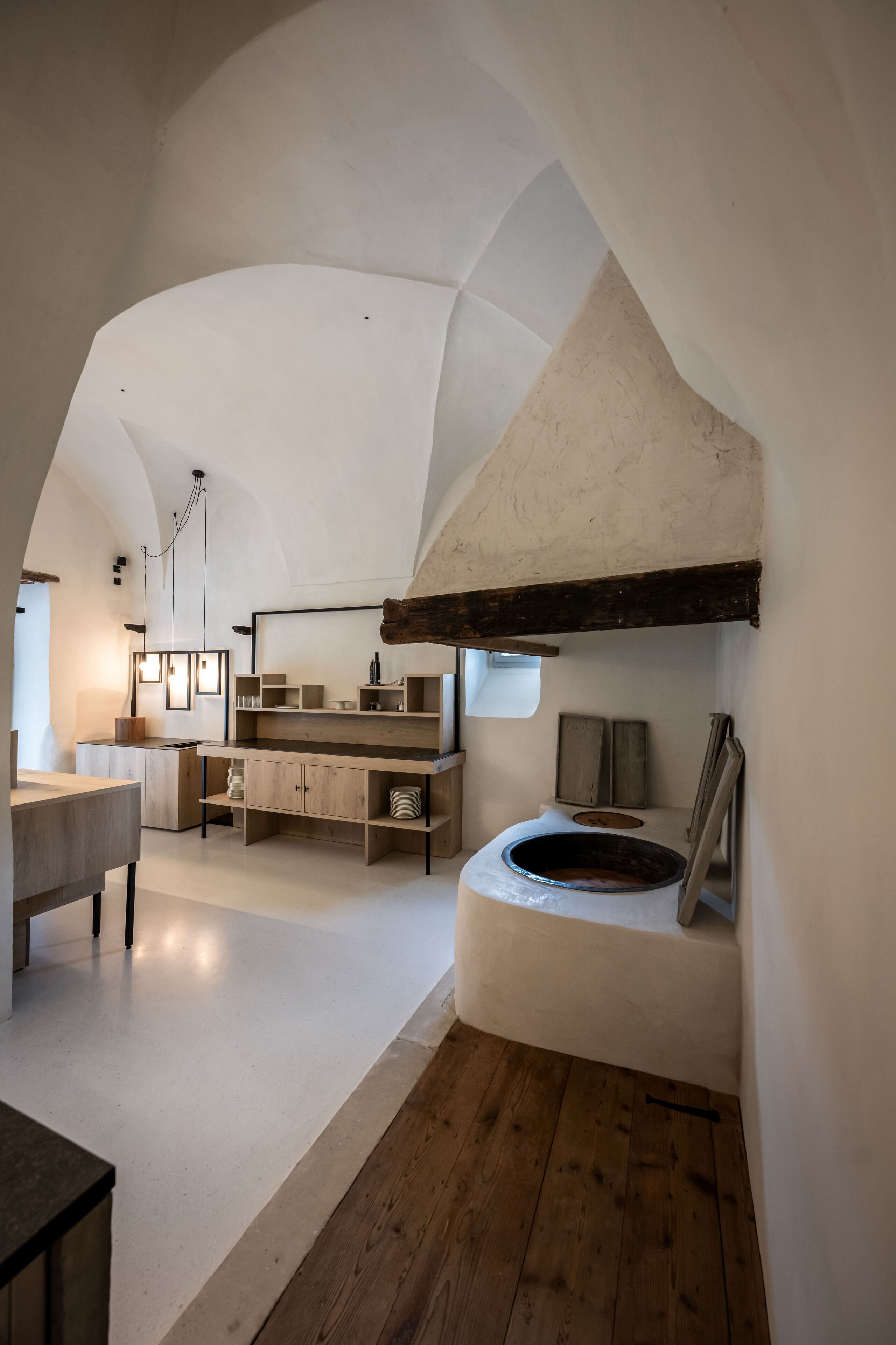 A spacious room with a wooden floor, a large white bathtub, and a wooden bench.
