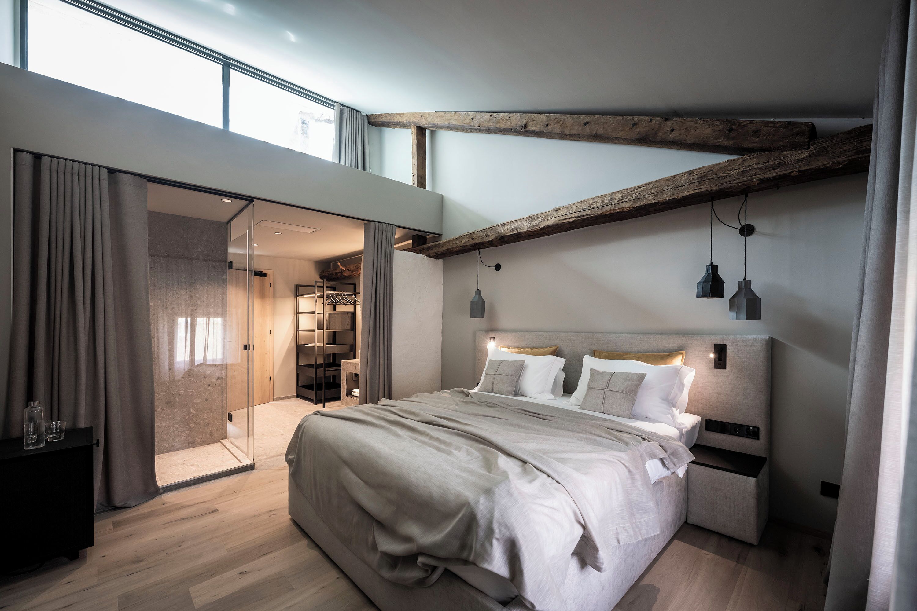 Une chambre moderne avec un grand lit, une armoire intégrée et une porte en verre donnant sur la salle de bain.