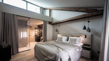 Une chambre moderne avec un grand lit, une armoire intégrée et une porte en verre donnant sur la salle de bain.