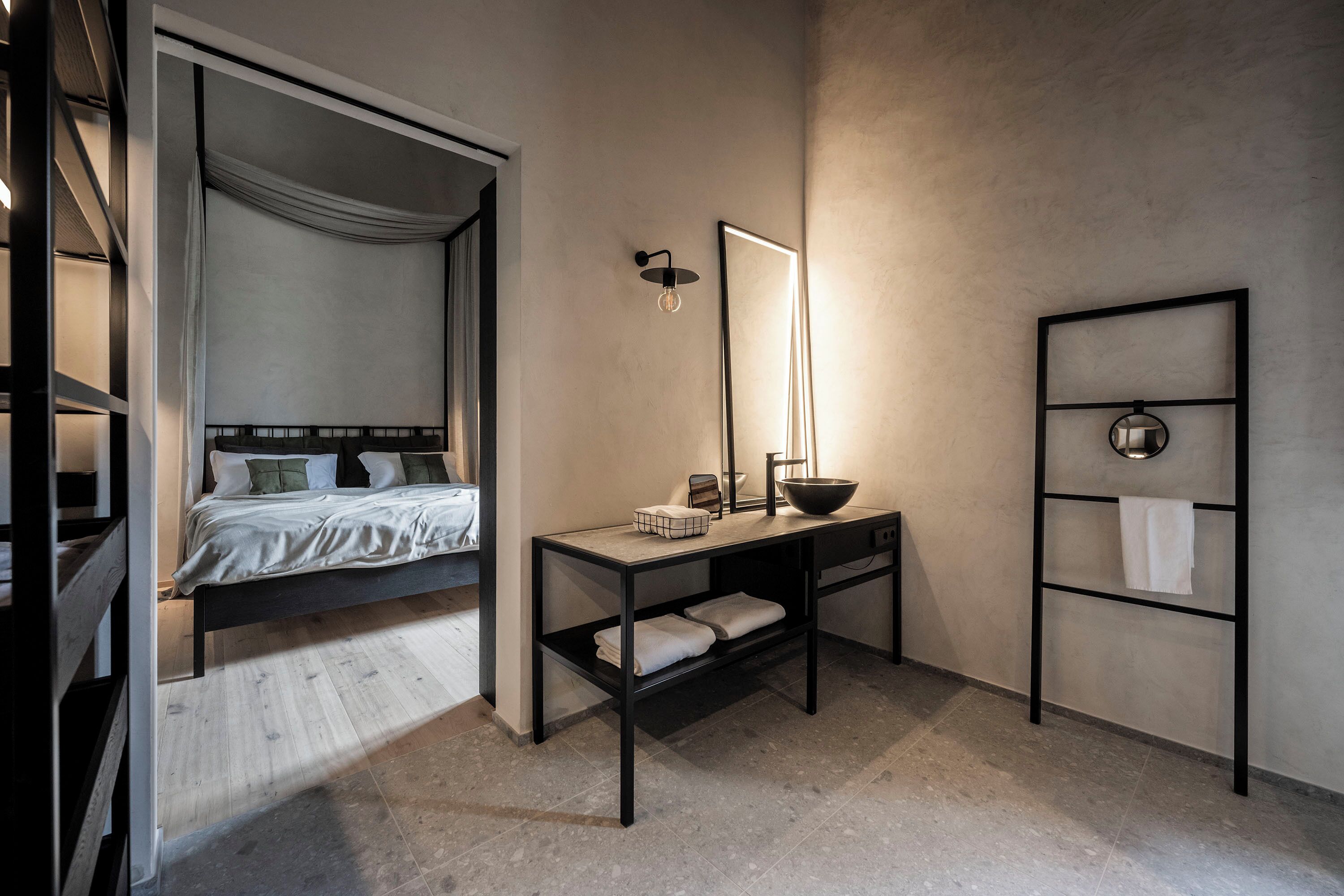 Quarto moderno com cama, mesa de cabeceira e um espelho grande.