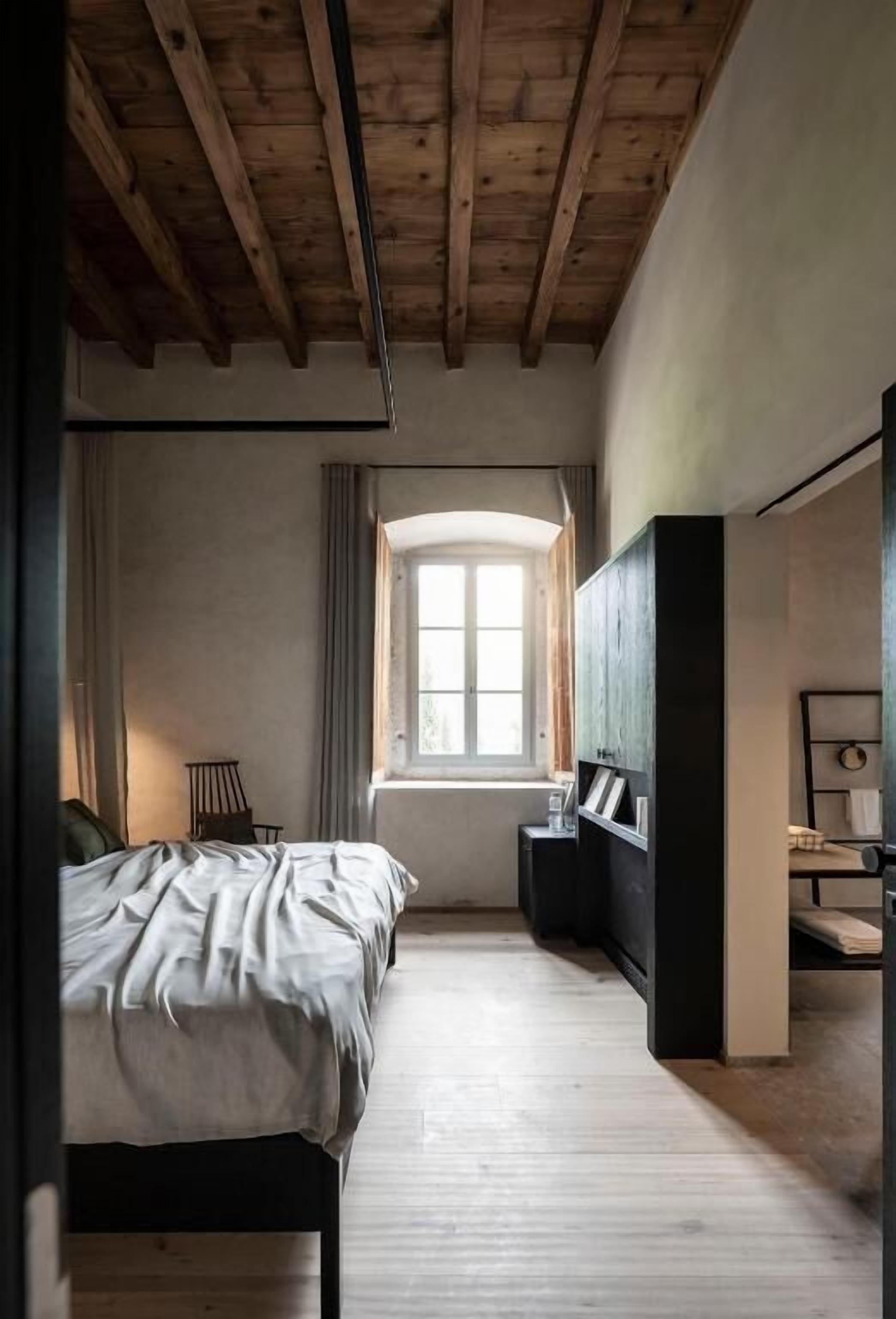 A bedroom with a wooden ceiling, a bed, a window, and a wardrobe.