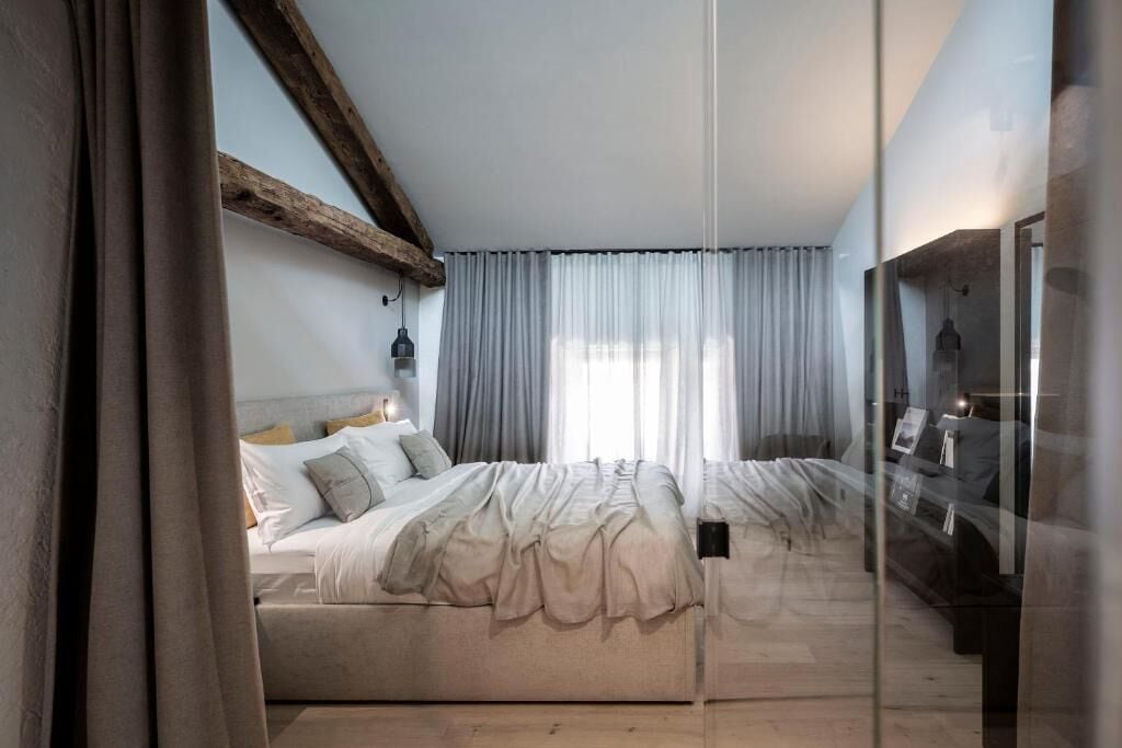 A bedroom with a large bed, a mirror, and a wooden ceiling beam.