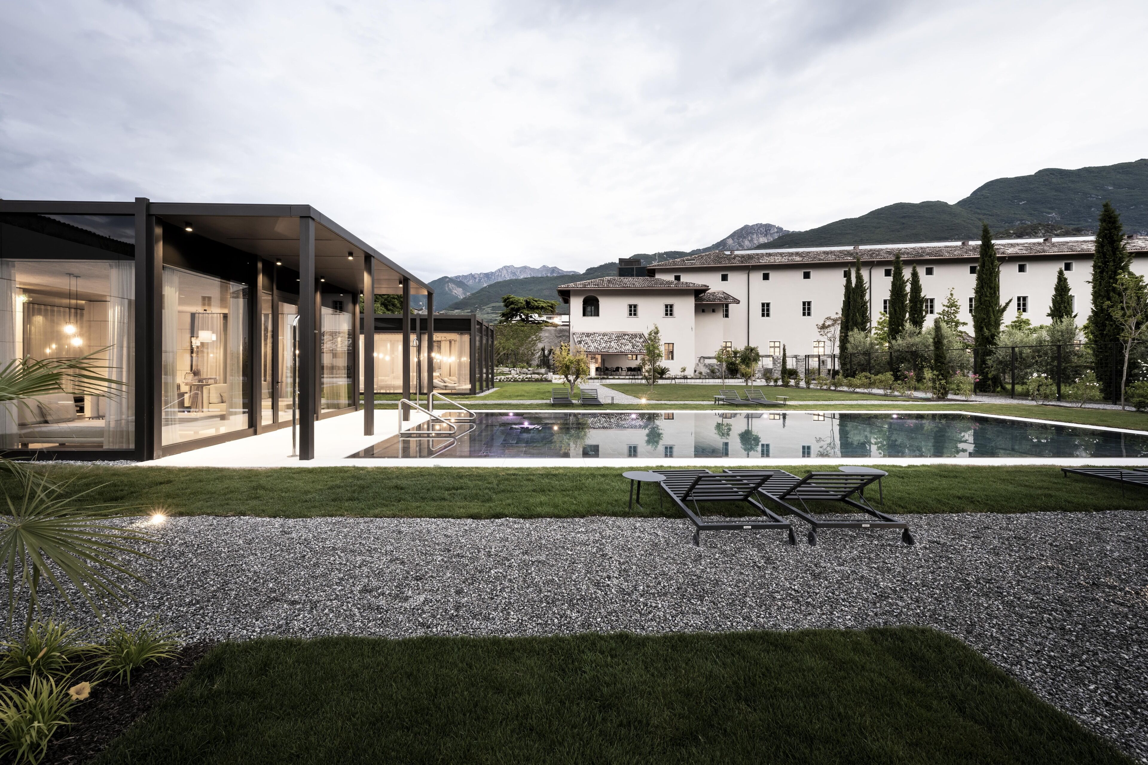 Un bâtiment moderne doté d’une façade en verre, d’une piscine et d’une pelouse bien entretenue.