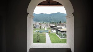 An arched view of a courtyard with a pool, a small tree, and a mountain in the background. - Monastero ARX VIVENDI (Arco)