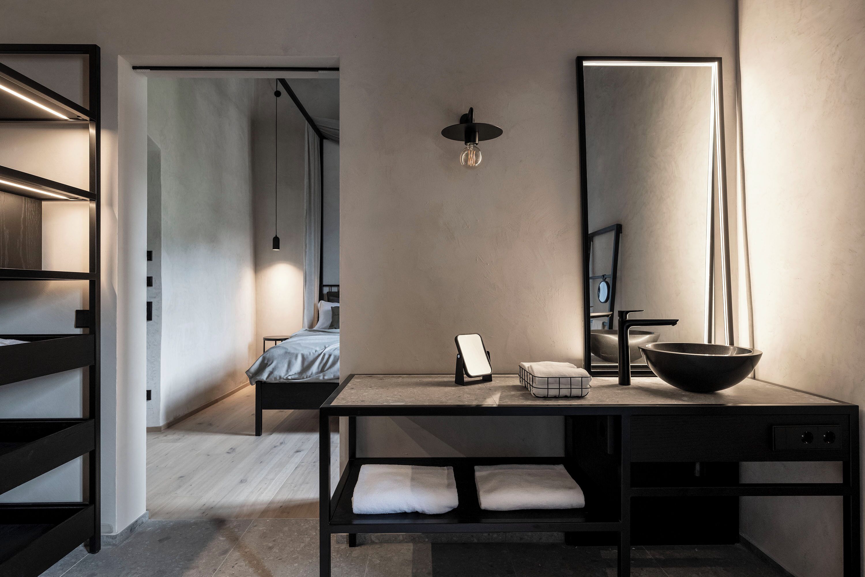 A modern bedroom with a bed, bedside table, and a large mirror.
