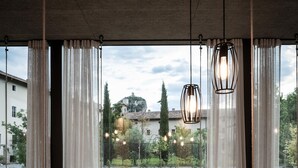 A modern bedroom with a hanging bed, large windows, and a view of a garden. - Monastero ARX VIVENDI (Arco)