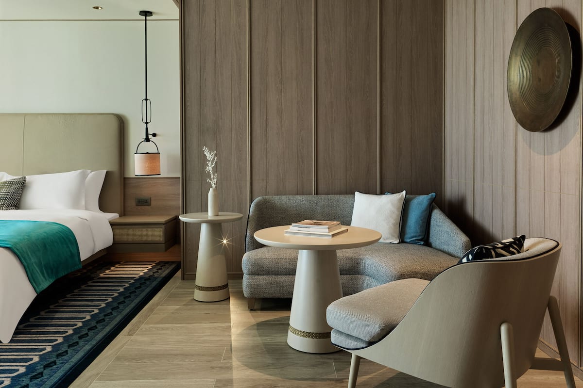 Ein modernes Hotelzimmer mit Bett, Sofa, einem kleinen Tisch und einer dekorativen Vase.