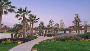 A landscaped garden with palm trees, a wooden walkway, and a gazebo. - City of Dreams Mediterranean - Integrated Resort, Casino & Entertainment (Limassol)