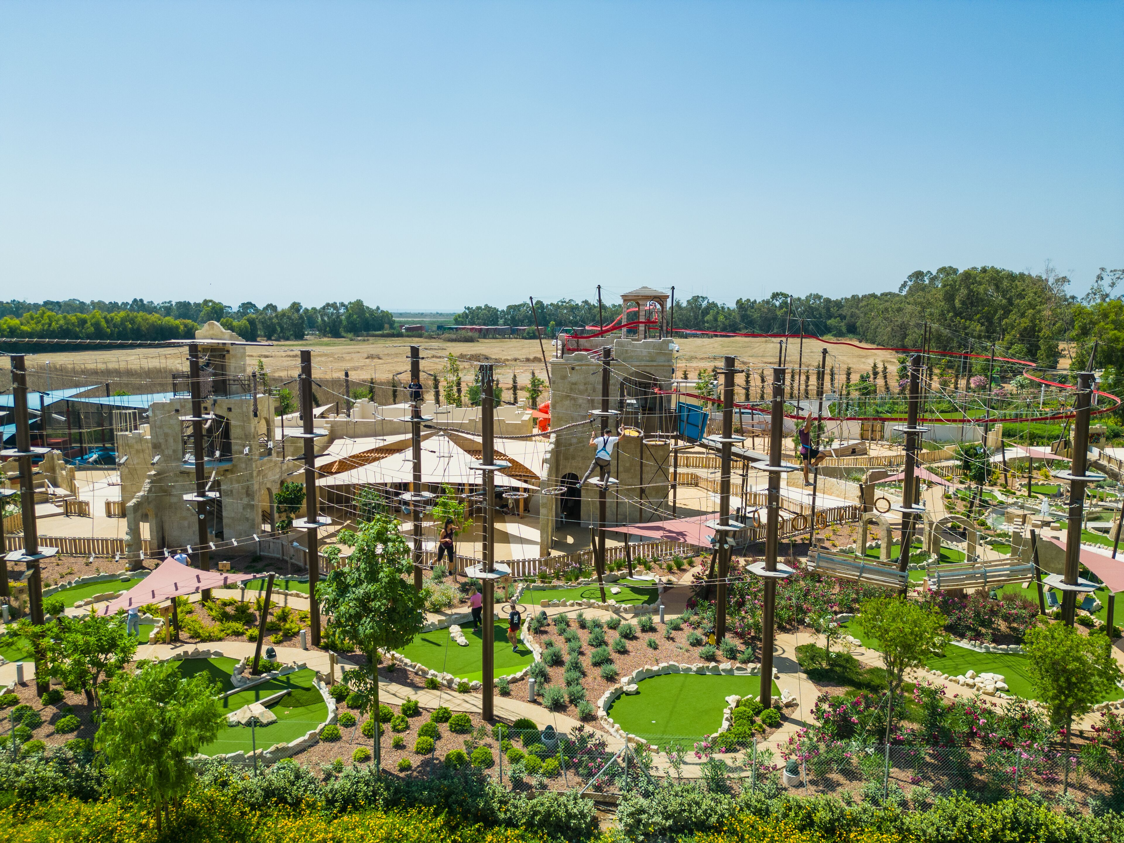 En udendørs oplevelsespark med klatrestrukturer, rebstier og anlagte haver.