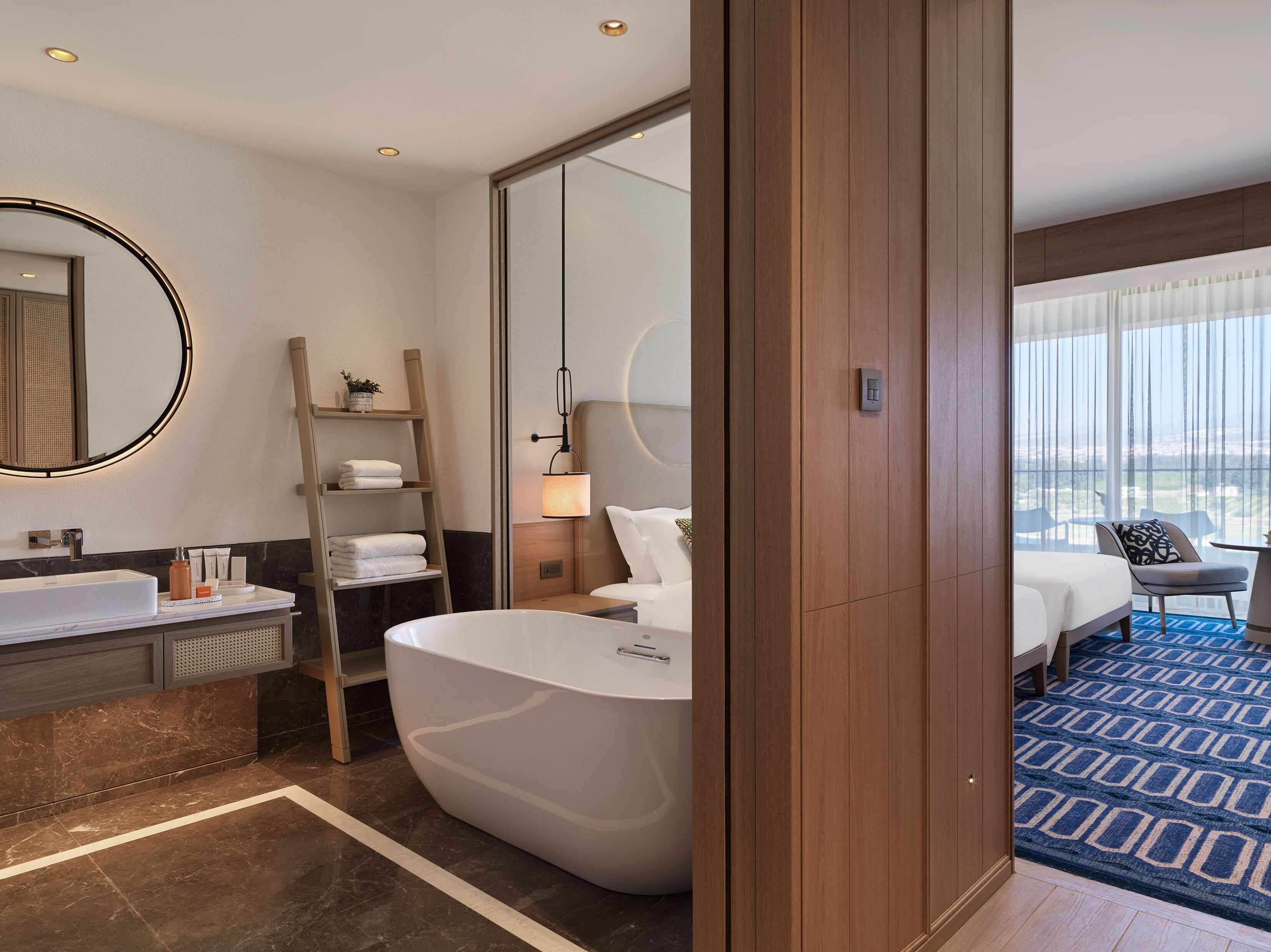 Un baño de hotel moderno con una bañera grande, un tocador con espejo y una zona de ducha.