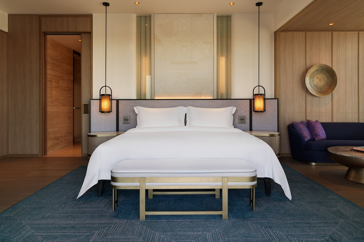 Ein modernes Hotelzimmer mit einem großen Bett, zwei Nachttischen, einem Sofa und einem dekorativen Wandbild.