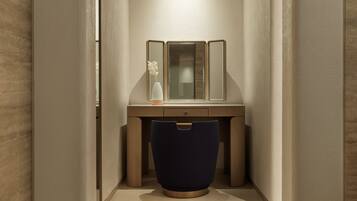A narrow hallway with a wooden vanity, a mirror, and a vase with dried flowers.