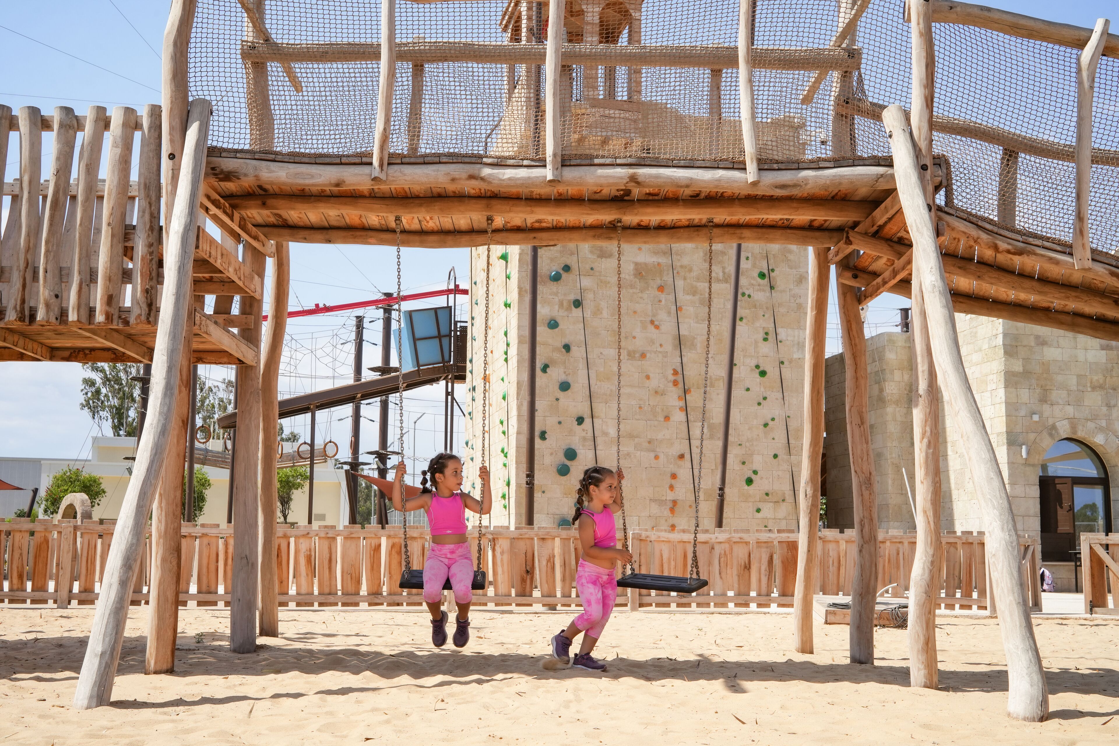 A playground with a climbing wall and swings.
