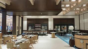 A spacious hotel lobby with multiple seating areas, a bar, and a reception desk.