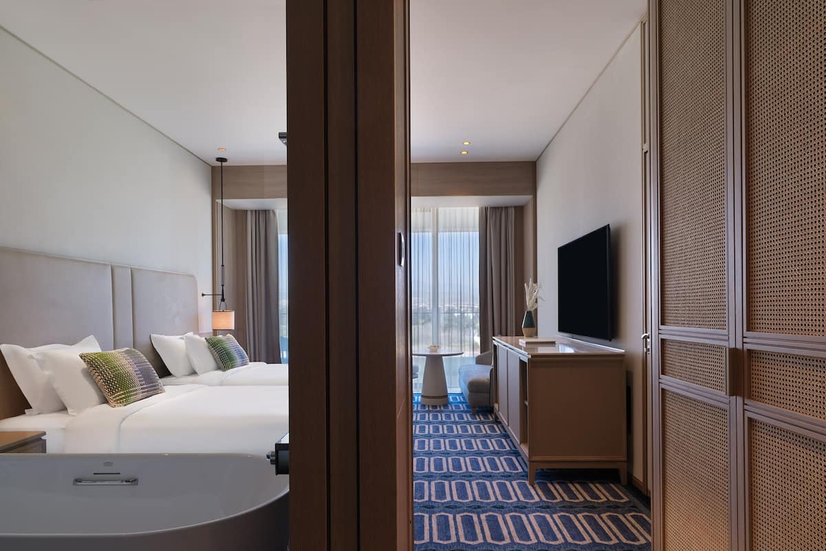 Ein Hotelzimmer mit Bett, Schreibtisch, Fernseher und Blick auf die Stadt.