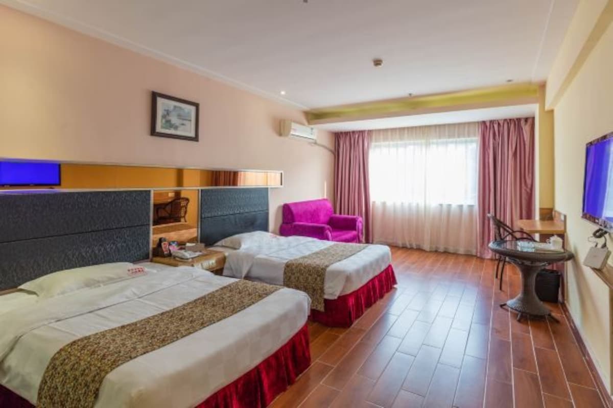 Habitación de hotel con dos camas, un escritorio, una silla y un televisor.