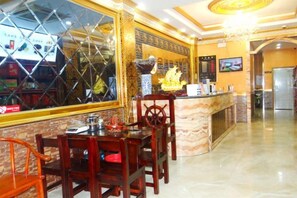 A restaurant with a marble counter, wooden chairs, and a decorative vase.