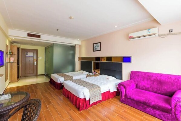 Quarto de hotel com duas camas, um sofá rosa e uma mesa pequena.