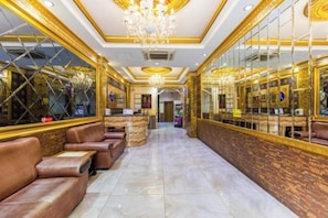 Un hall d’hôtel avec des fauteuils en cuir, un comptoir d’accueil et un lustre.