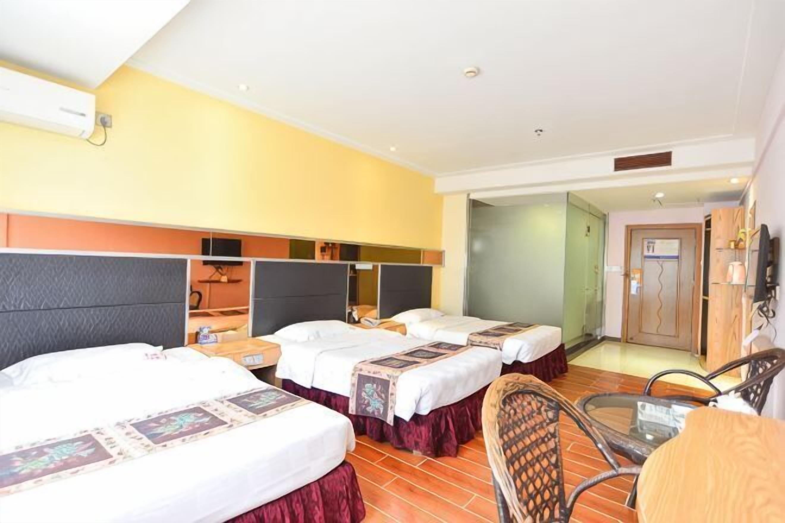 A hotel room with three beds, a small table, and a chair.