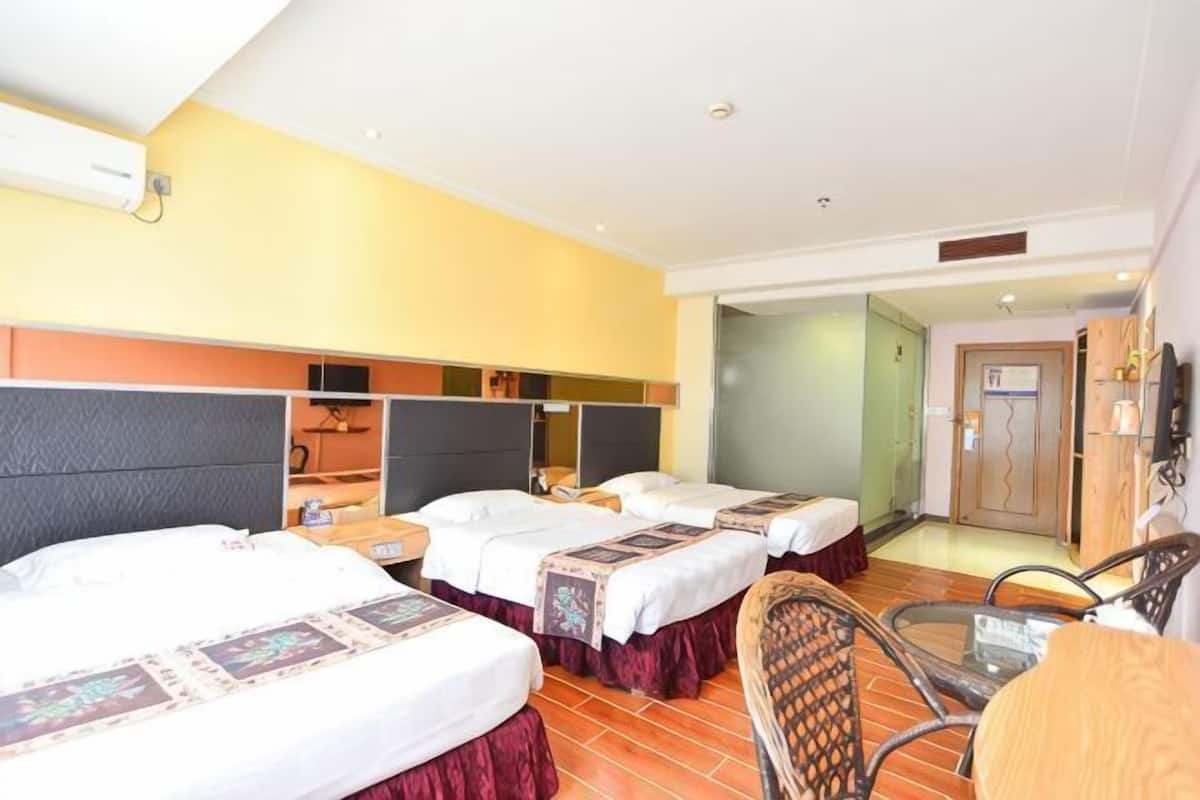 A hotel room with three beds, a small table, and a chair.