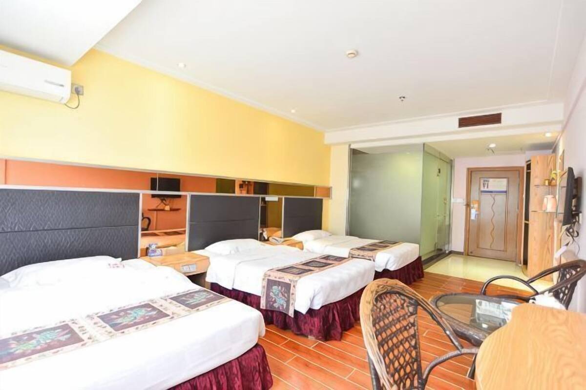 A hotel room with three beds, a small table, and a chair.
