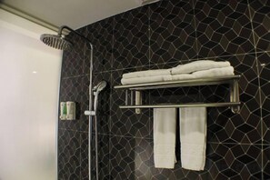Une salle de bain équipée d’une douche, d’un porte-serviettes et d’un distributeur de serviettes fixé au mur.