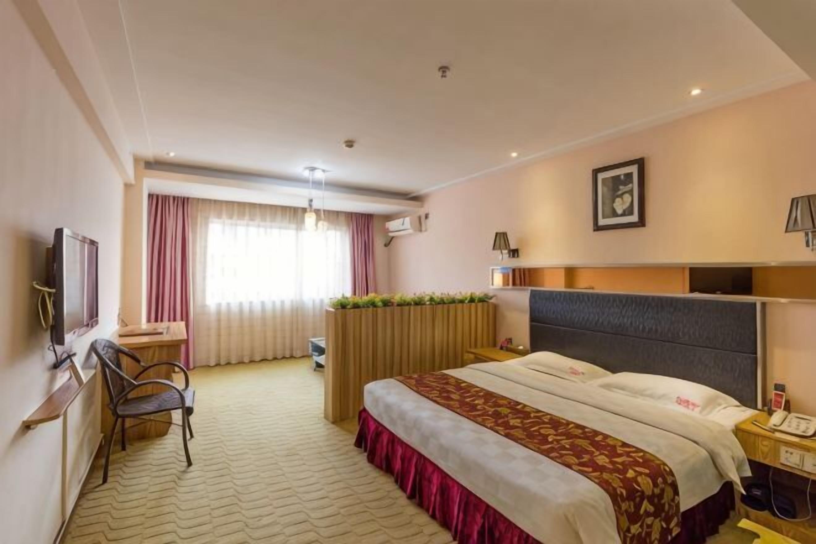 Une chambre d’hôtel équipée d’un lit, d’un bureau, d’une chaise, d’une télévision et d’une fenêtre avec des rideaux.