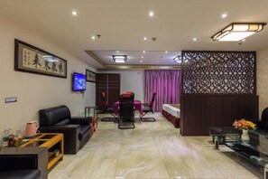 A modern living room with a sofa, TV, and a dining area with chairs and a table.