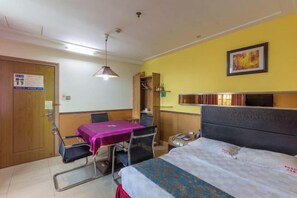 Une chambre d’hôtel équipée d’un lit, d’un bureau, d’une chaise, d’une table et d’un luminaire suspendu.